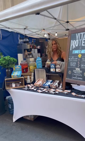 Veja o vídeo hilariante em que Jennifer Aniston vende barrinhas num mercado — e espicaça rumores