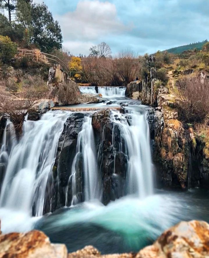 Esta praia fluvial entre montanhas é ideal para uma tarde de verão.  E tem uma cascata incrível